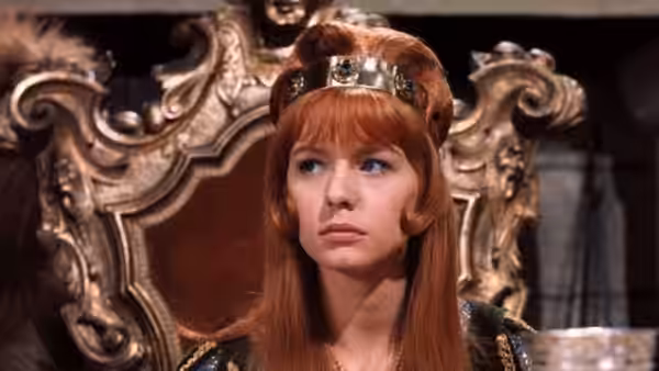 Francesca (Jane Asher) sits before an ornate throne in a jeweled crown