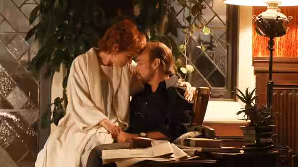 Gwen Verdon (Michelle Williams) leans toward Bob Fosse (Sam Rockwell) at a desk with open books
