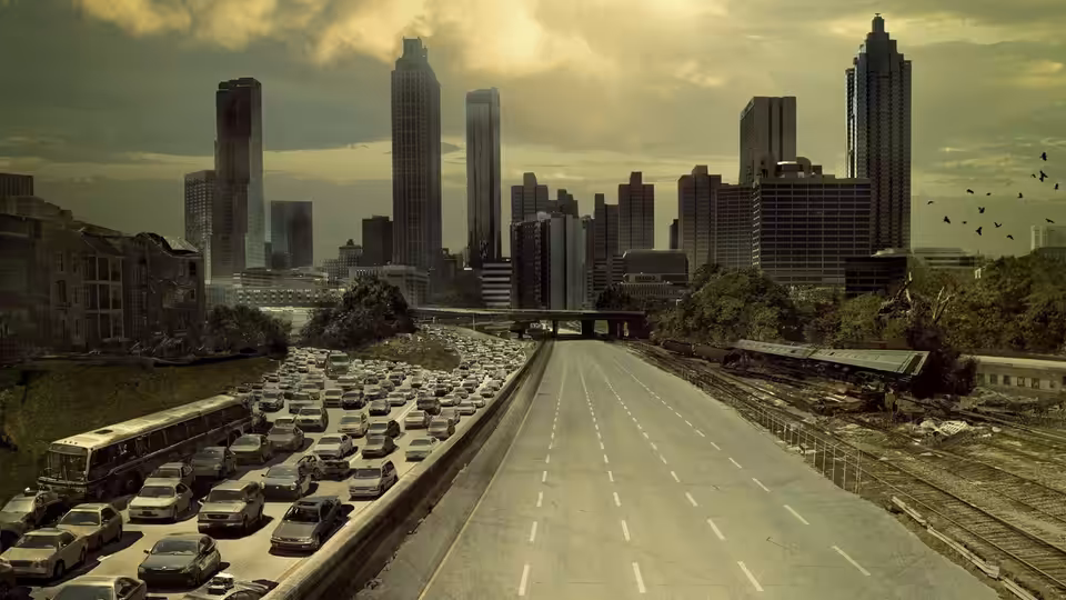 An empty highway clogged with abandoned vehicles leading into a ruined city