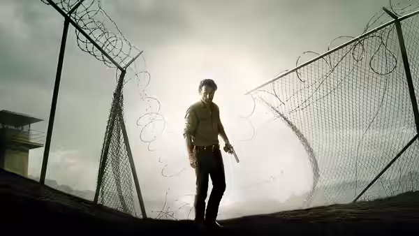 Rick Grimes (Andrew Lincoln) standing before a barbed wire fence holding a pistol