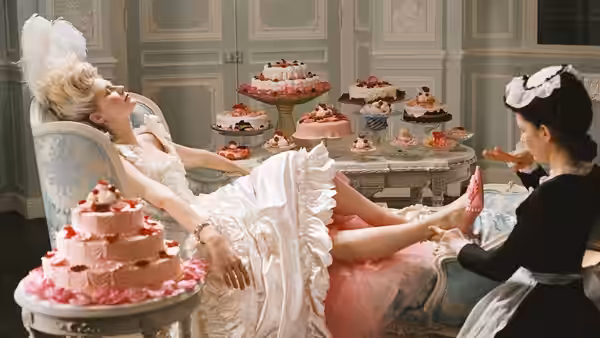 Marie Antoinette (Kirsten Dunst) reclines as a servant tends her feet among cakes