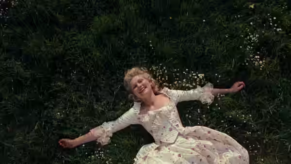 Marie Antoinette (Kirsten Dunst) lies among flowers on a dark garden lawn