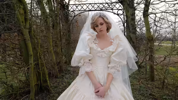 Diana (Kristen Stewart) stands in a wedding dress beneath a garden arch