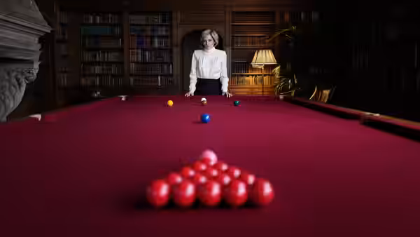 Diana (Kristen Stewart) stands at the far end of a snooker table in a library