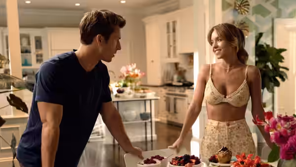 Ben (Glen Powell) and Bea (Sydney Sweeney) facing each other across a kitchen island with fruit