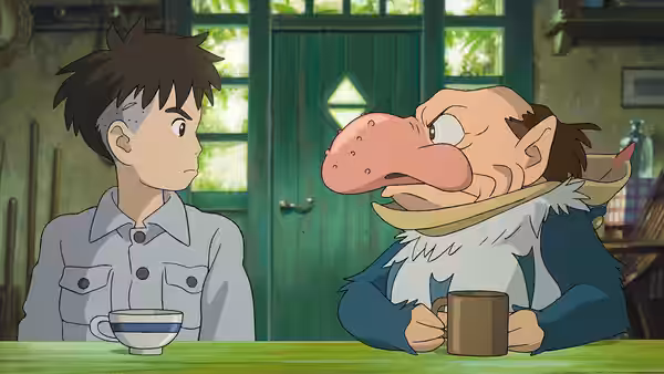 Mahito Maki sits across from a large-nosed creature at a wooden table