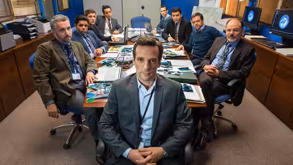 Guillaume Debailly (Mathieu Kassovitz) seated before colleagues at a briefing table