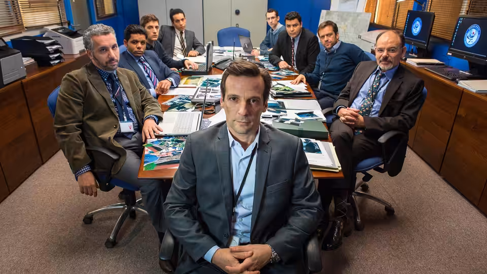 Guillaume Debailly (Mathieu Kassovitz) seated before colleagues at a briefing table