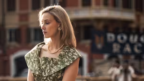 a woman in a green floral dress standing before a building