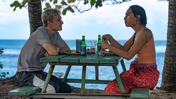 Thomas Rongen (Michael Fassbender) and Jaiyah (Kaimana) eating at a beachside picnic table
