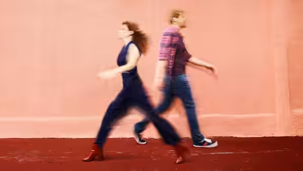 Jimmy (Chris Geere) and Gretchen (Aya Cash) walking past a pink wall