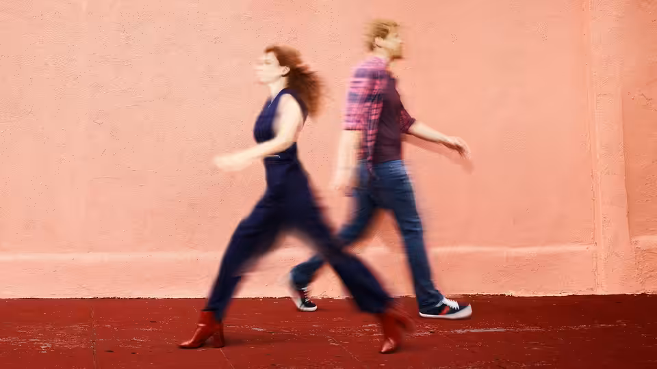 Jimmy (Chris Geere) and Gretchen (Aya Cash) walking past a pink wall