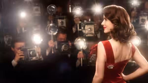 Midge Maisel (Rachel Brosnahan) posing in a red dress before photographers