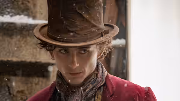 Willy Wonka (Timothée Chalamet) gazing ahead as snow falls around him