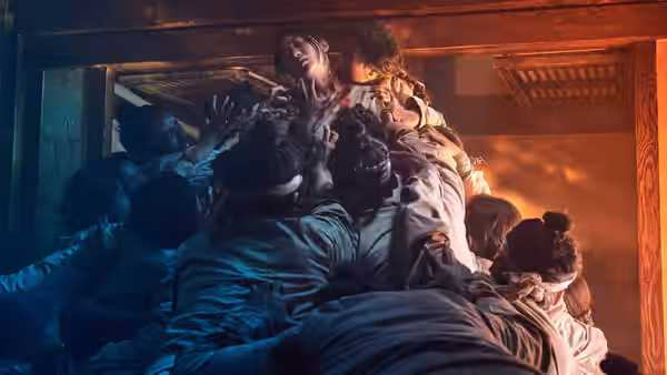 Crowd of people climb and struggle over each other inside a burning building