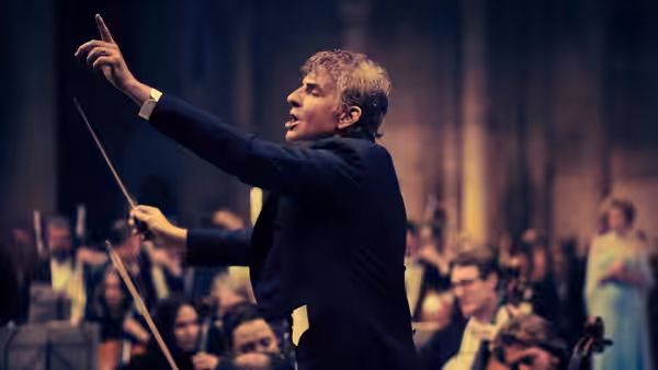 Leonard Bernstein (Bradley Cooper) conducting an orchestra with baton raised