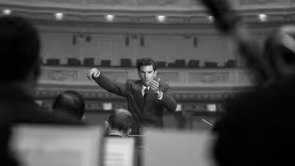Leonard Bernstein (Bradley Cooper) conducting with raised fist in a hall