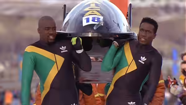 Two bobsledders carry their numbered sled across the track
