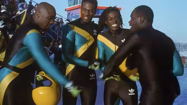 The Jamaican bobsled team in matching uniforms gathers around a teammate for a handshake
