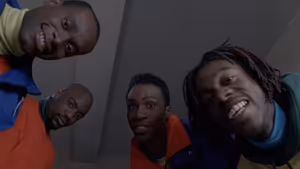 Four teammates lean over the camera, smiling down into the frame