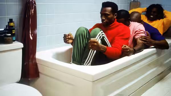 Four teammates squeeze into a bathtub, gripping the sides as they sit in a row