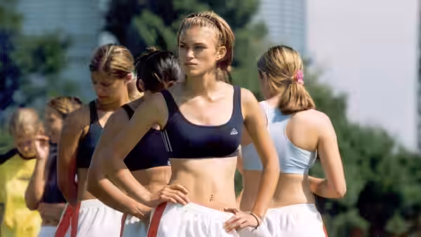 Jules (Keira Knightley) stands hands on hips among teammates during football training