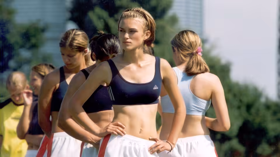 Jules (Keira Knightley) stands hands on hips among teammates during football training