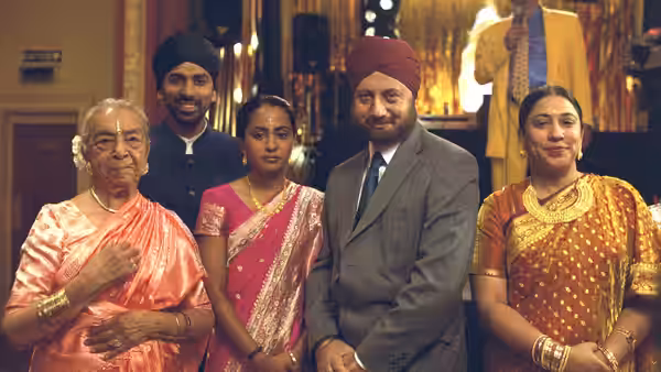 A Sikh family poses together in formal clothing at a gathering