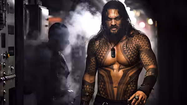 Arthur Curry walks through a steam-filled industrial passage in his scaled armor