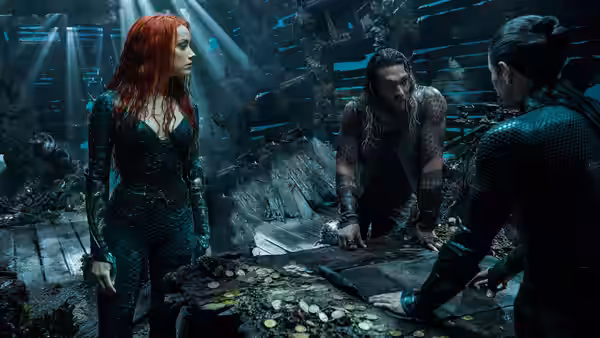 Mera and Arthur Curry confer with another man over a map in a flooded ruin