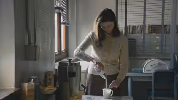 Eileen Dunlop (Thomasin McKenzie) pouring milk into a cup in an office