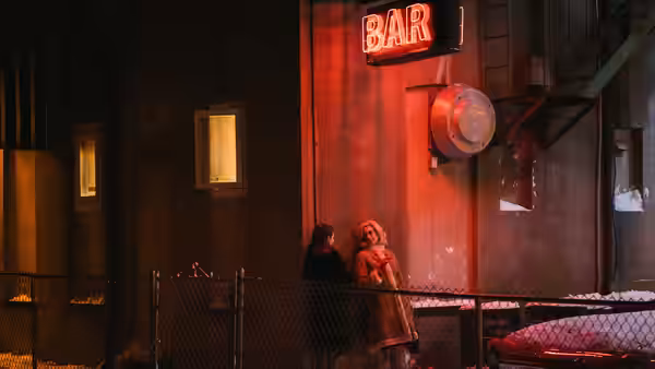 Eileen (Thomasin McKenzie) and Rebecca (Anne Hathaway) standing outside a bar at night