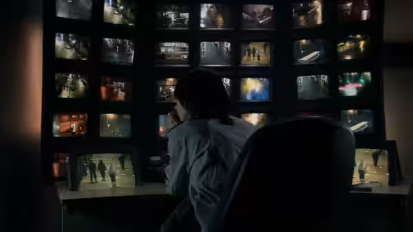 Jackie (Kate Dickie) monitors a wall of surveillance screens in the control room