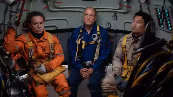 Finn Cole, Woody Harrelson and Simu Liu in safety harnesses inside a vessel