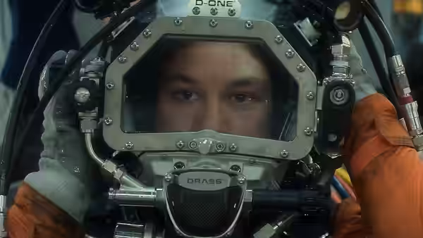 Finn Cole as Chris Lemons wearing a diving helmet inside a chamber