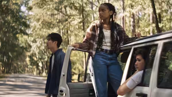 Day (Akira Jackson) stands by an open car door in the woods