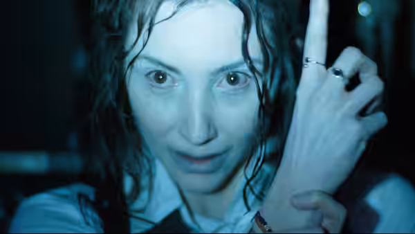 a woman with wet hair raising her hand with rings in dim light