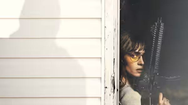 a woman with glasses holding a rifle and peeking from a doorway