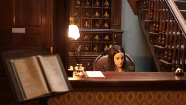 Receptionist (Carly-Sophia Davies) working at the front desk of a hotel