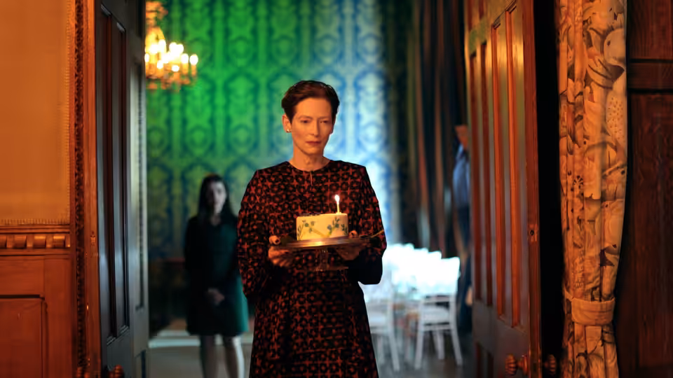 Julie (Tilda Swinton) holding a birthday cake in a hotel hallway