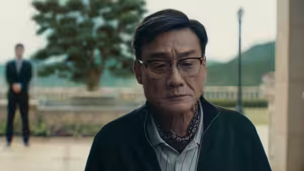 An older man with glasses standing in front of a tree