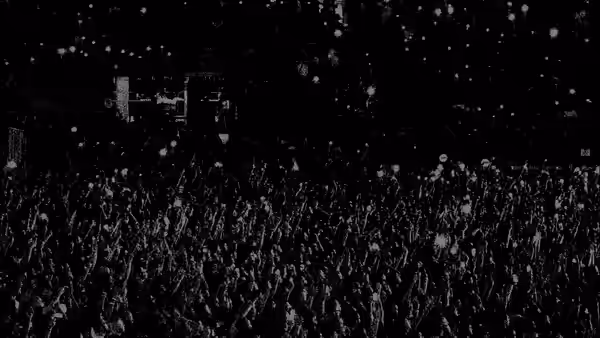Huge crowd raising hands at a concert with confetti falling from above