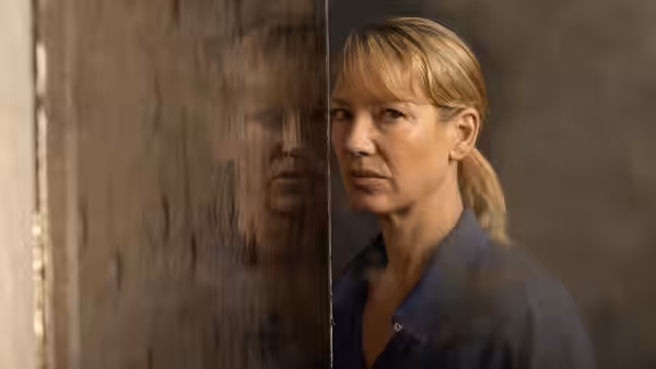 Antigone 'Tig' Pollard (Anna Torv) beside a reflective panel, studying her reflection