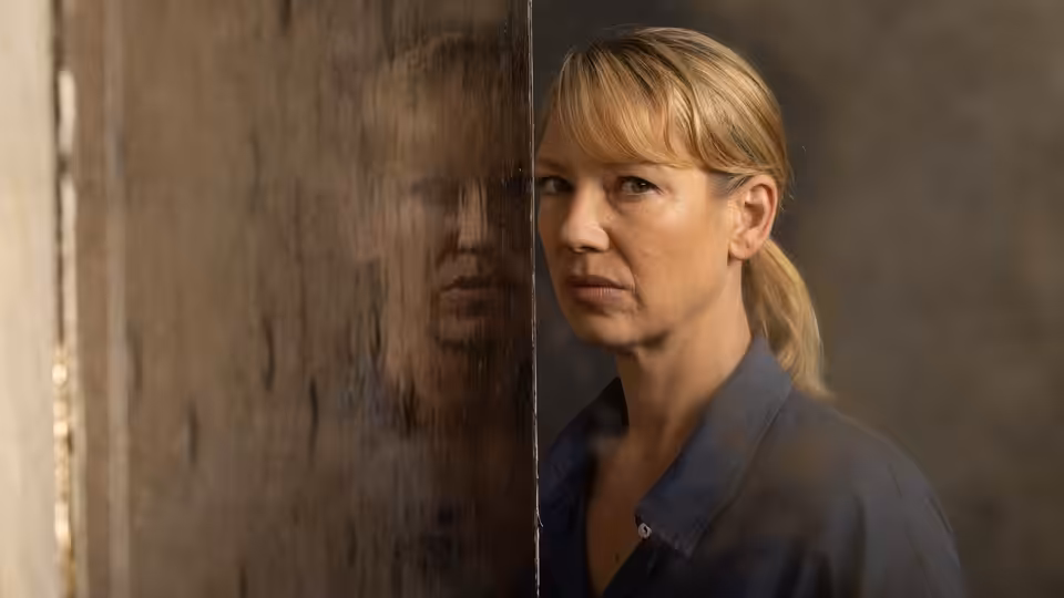 Antigone 'Tig' Pollard (Anna Torv) beside a reflective panel, studying her reflection