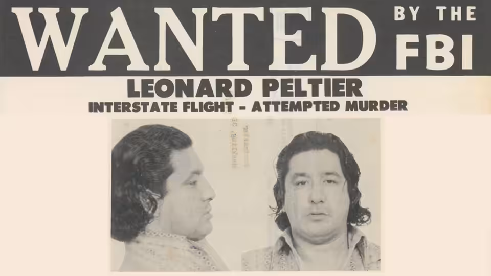 A wanted poster displays Leonard Peltier’s name and front and profile booking photographs