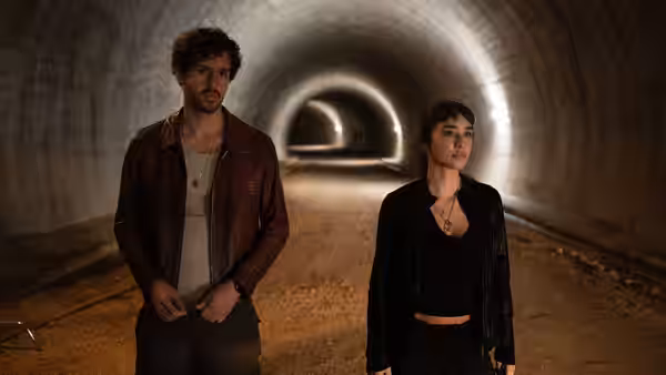 A young man and woman stand together in an underground tunnel