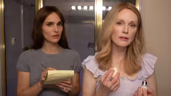 Elizabeth (Natalie Portman) holds a notepad beside Gracie (Julianne Moore) applying makeup