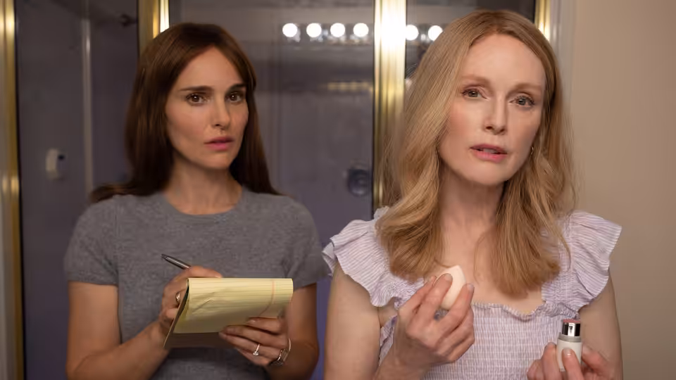 Elizabeth (Natalie Portman) holds a notepad beside Gracie (Julianne Moore) applying makeup