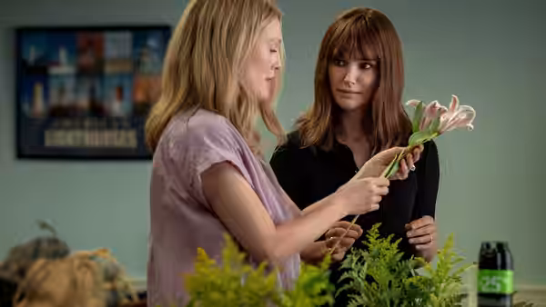 Gracie (Julianne Moore) shows flowers to Elizabeth (Natalie Portman) in a plant-filled room