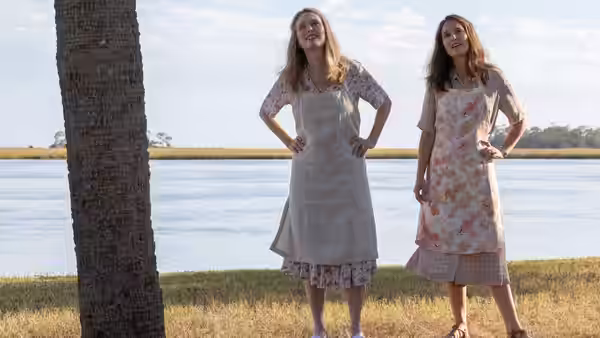 Gracie (Julianne Moore) and Elizabeth (Natalie Portman) stand with hands on hips by water
